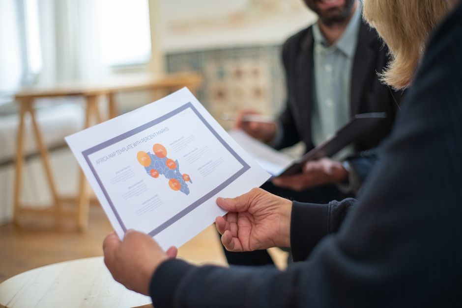 Three professionals discussing a data presentation in an office setting.